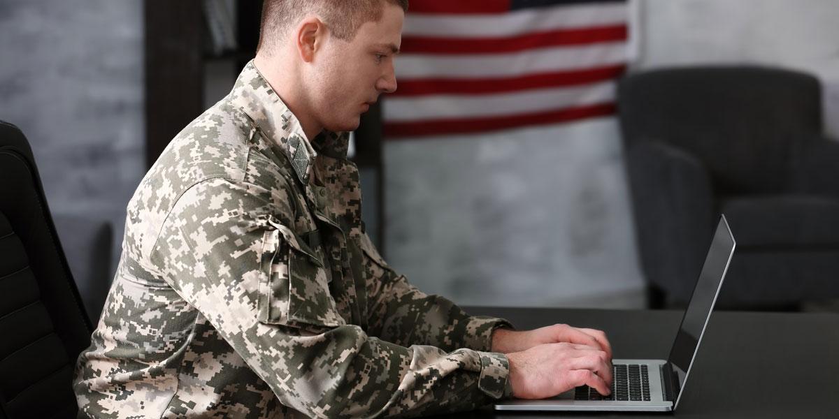 一个穿制服的军人在资源中心用笔记本电脑.
